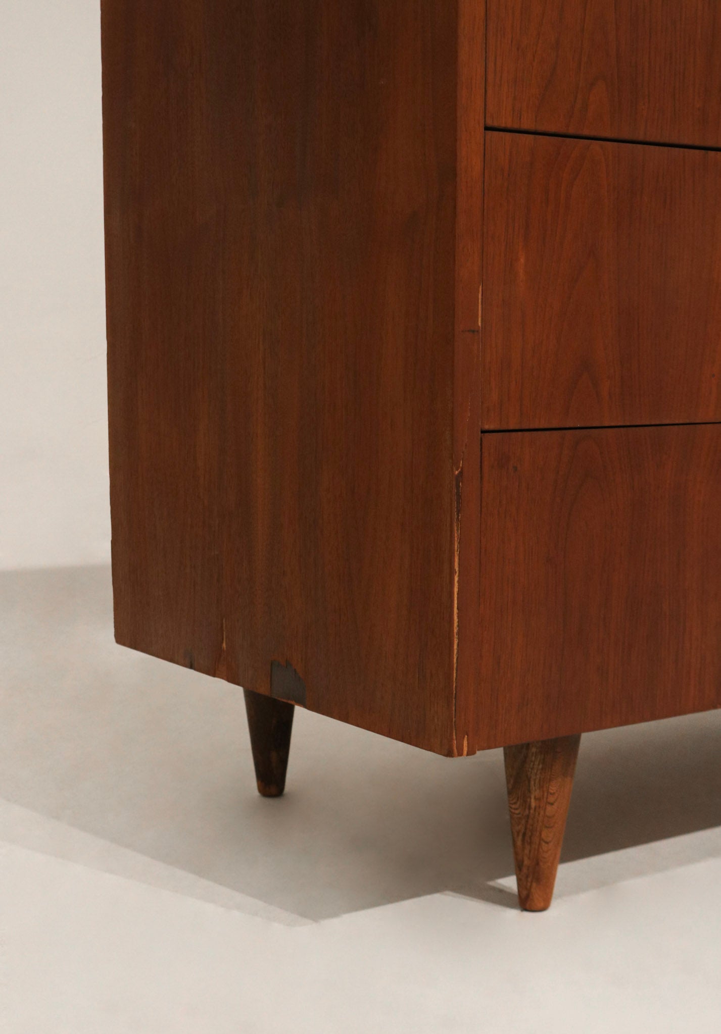 Lower corner detail showcasing tapered leg design in walnut wood
