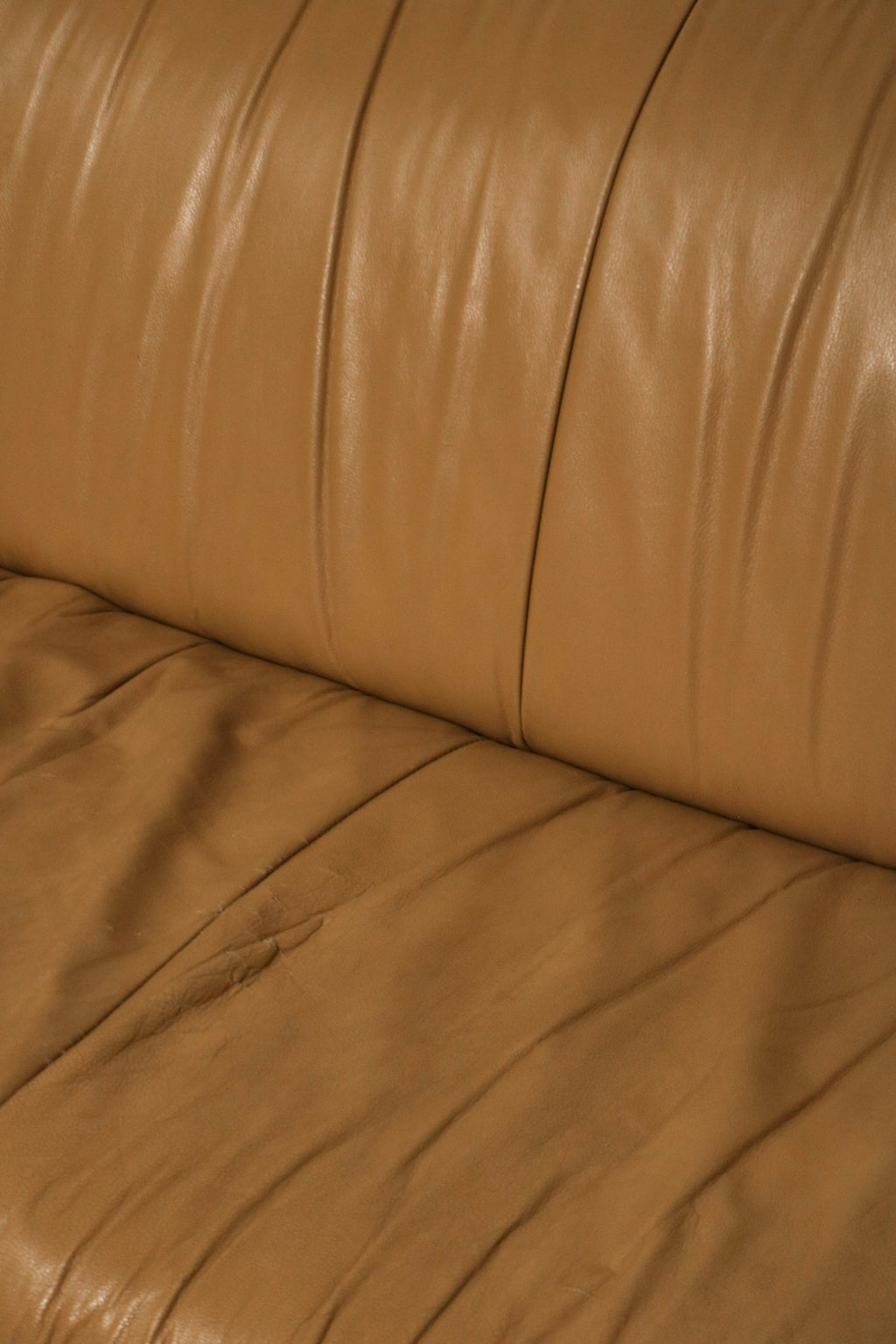 Texture close-up showing the aged, authentic leather grain in beige brown