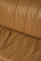 Texture close-up showing the aged, authentic leather grain in beige brown