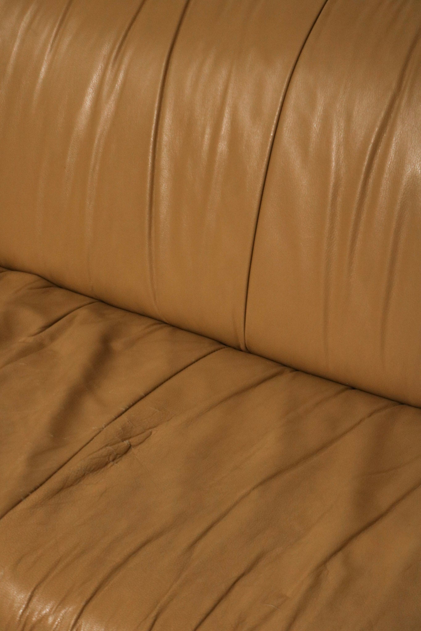 Texture close-up showing the aged, authentic leather grain in beige brown