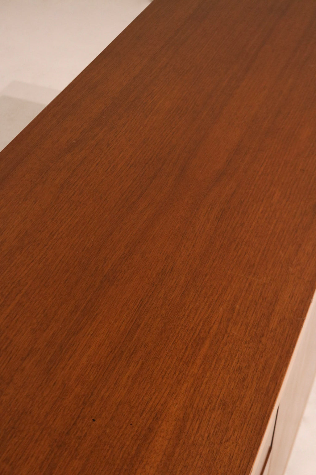 Side angle of walnut credenza capturing elegant lines and warm mid-century design