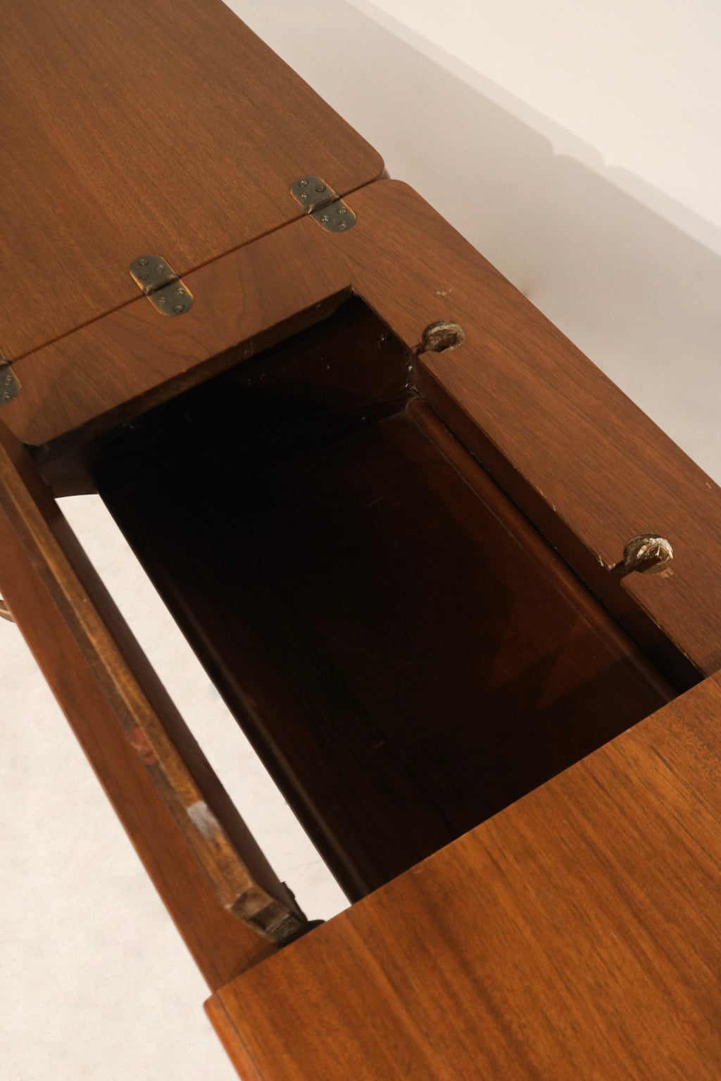 Detail: underside and extension mechanism of walnut wood desk showing leaf hinges, sliding supports and vintage construction details