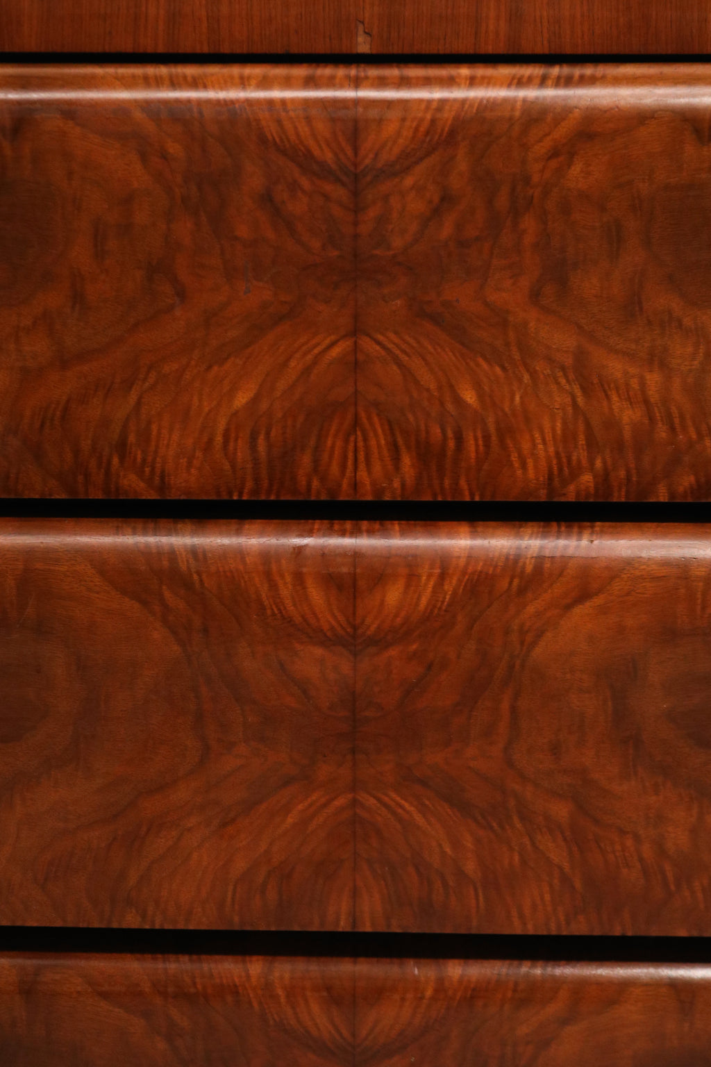 Close-up of burlwood grain texture on dresser top surface in warm natural wood tones
