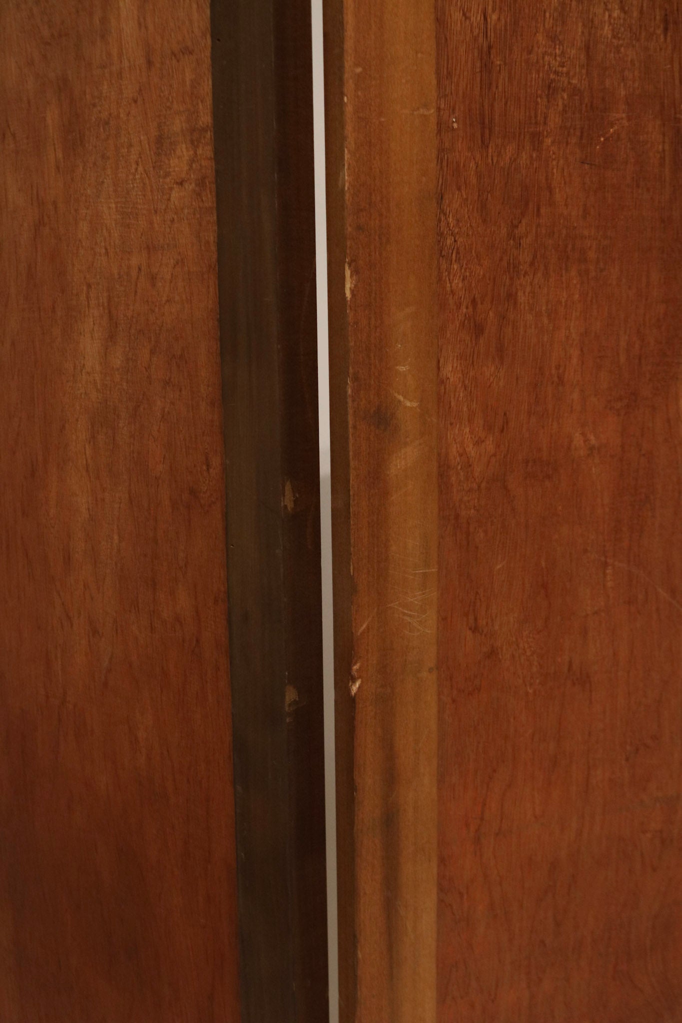 Detail of panel edge and hinge construction in pine wood, showing metal hardware, dovetail joints and hand-finished texture.