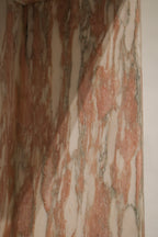 Close detail showing pink veining patterns, natural stone variations, honed spots and high-polish finish on marble surface.