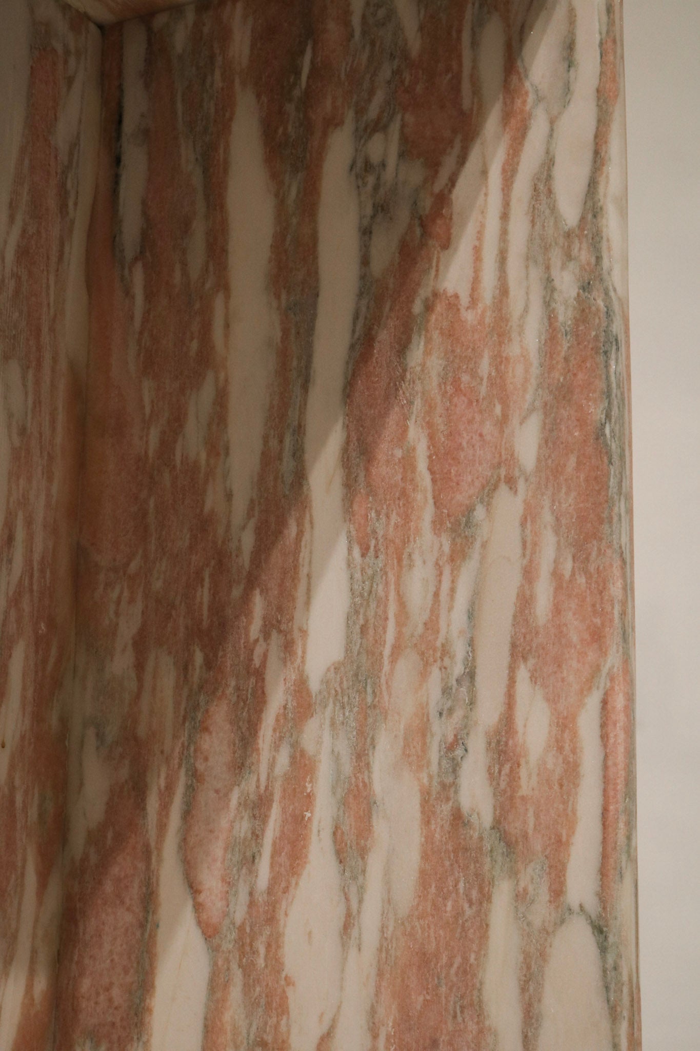 Close detail showing pink veining patterns, natural stone variations, honed spots and high-polish finish on marble surface.
