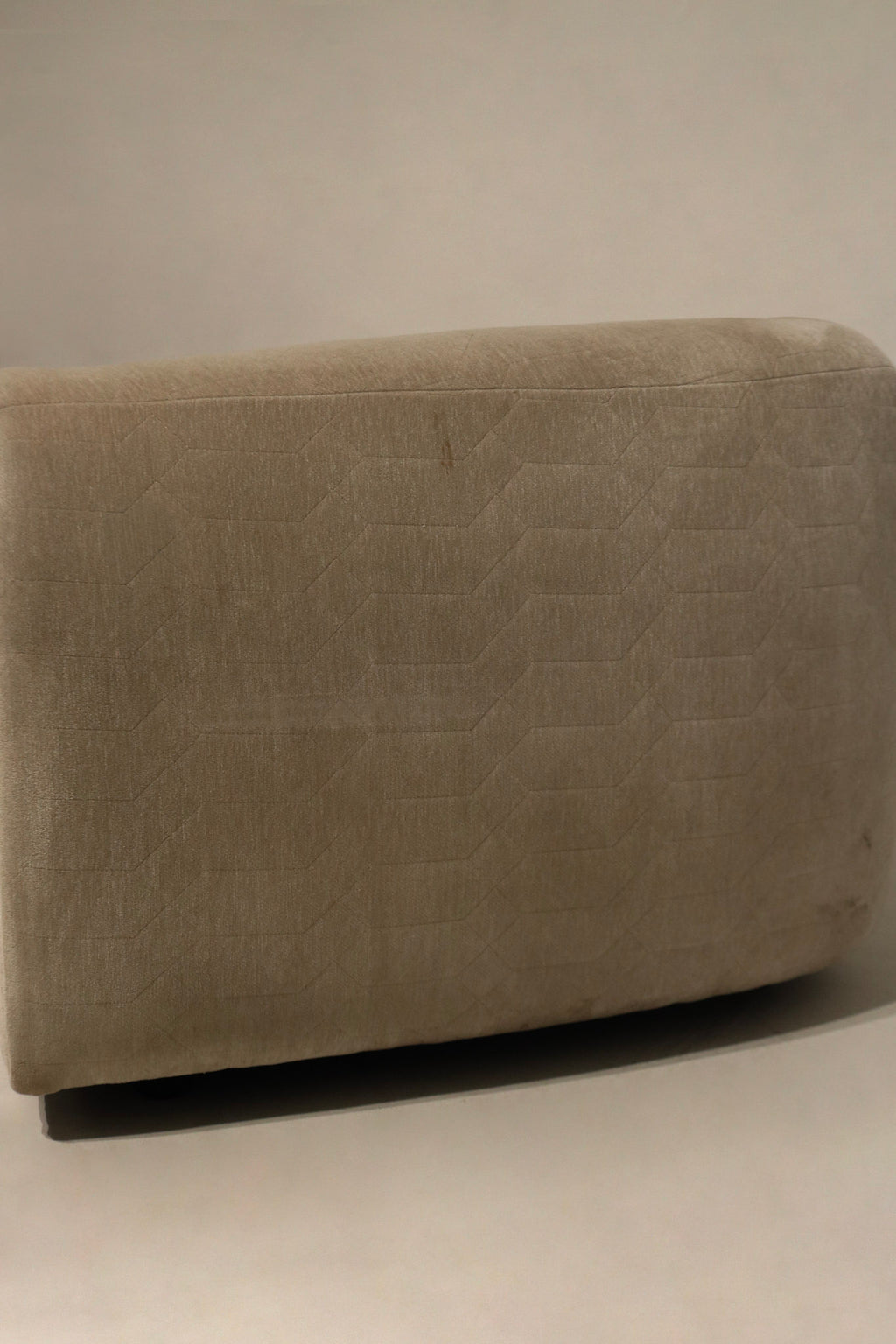 Armrest close-up of champagne velvet fabric, smooth velvet surface, gentle wear along edge, showing cushion support and upholstery finish