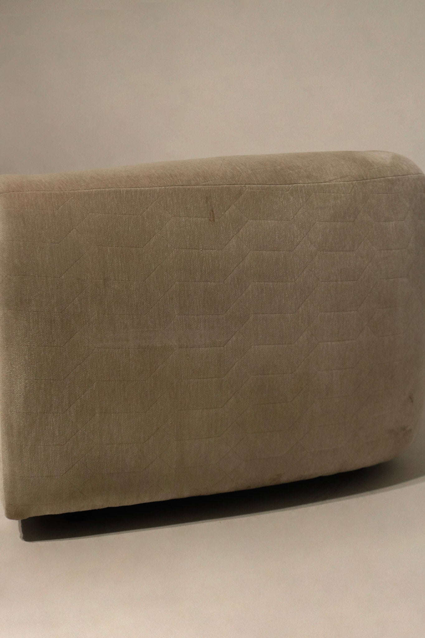 Armrest close-up of champagne velvet fabric, smooth velvet surface, gentle wear along edge, showing cushion support and upholstery finish