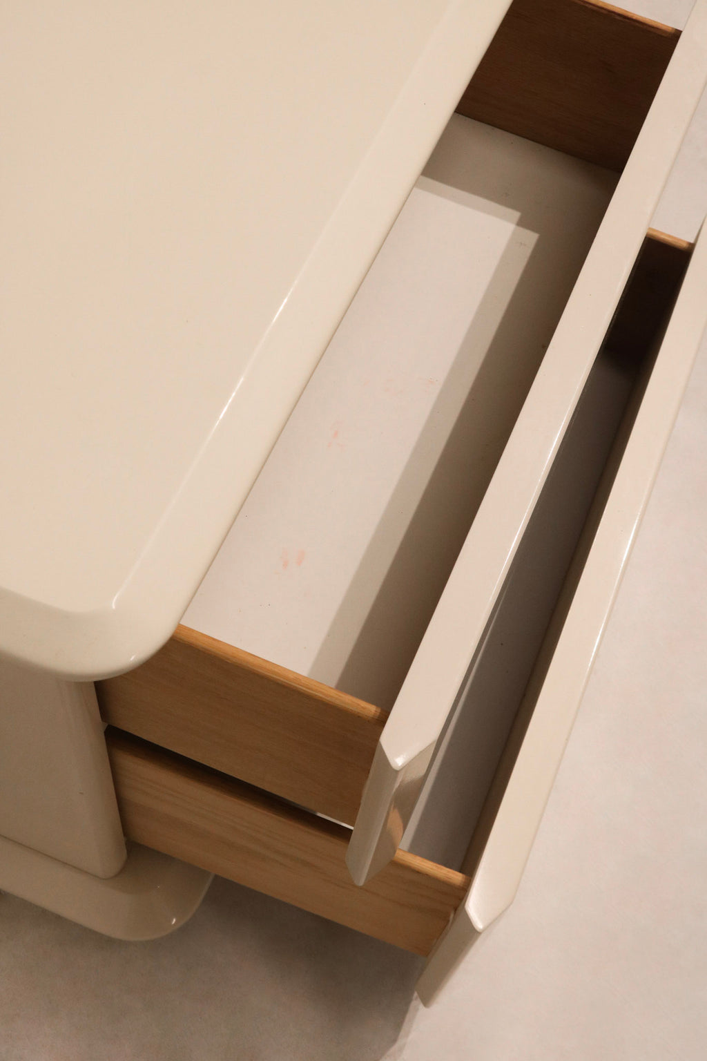 Close-up of white lacquered wood finish, highlighting smooth surface and minor wear on drawers