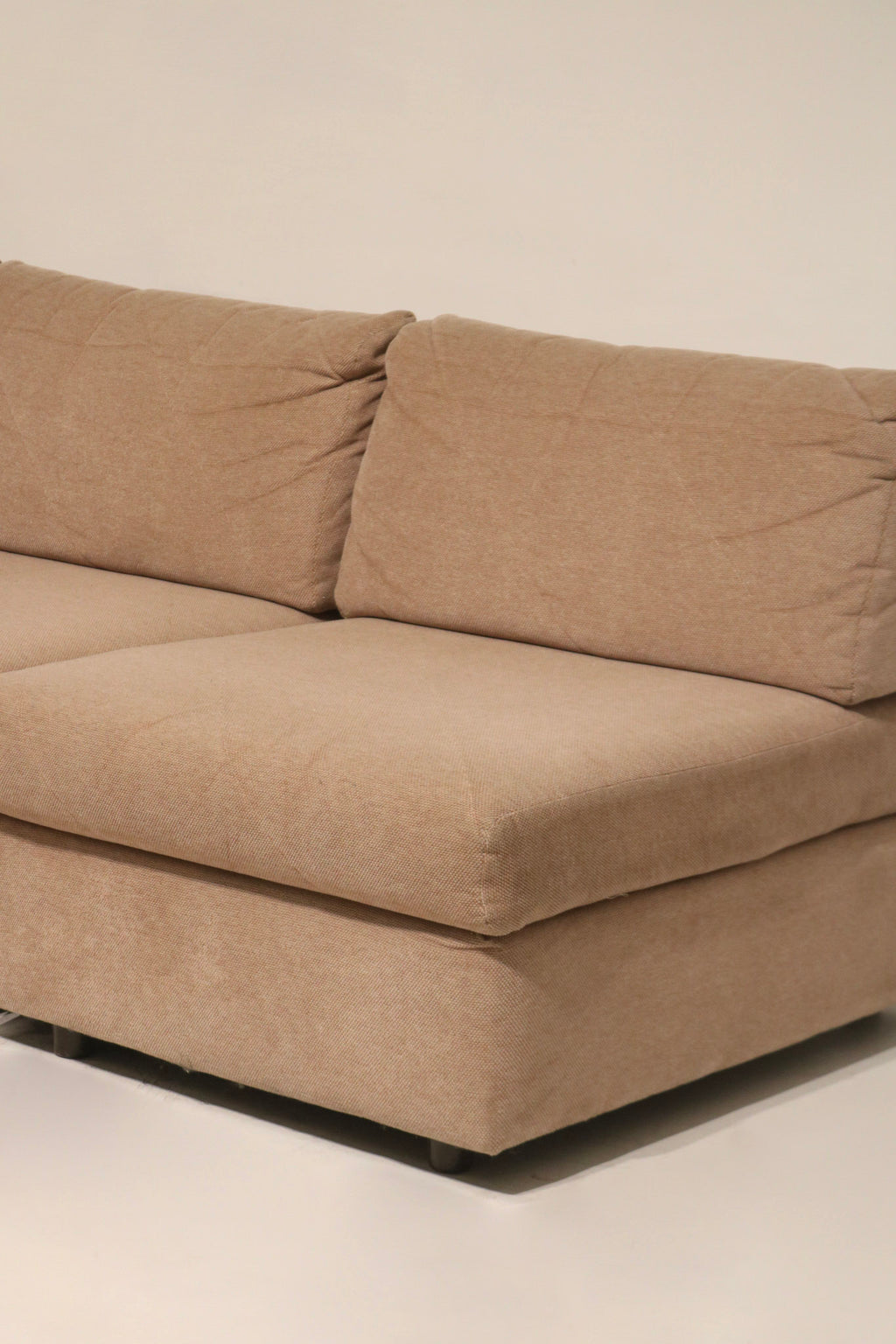 Arm profile close-up of fabric sofa couch showing rounded arm, fabric grain and edge stitching on vintage brown-pink upholstery