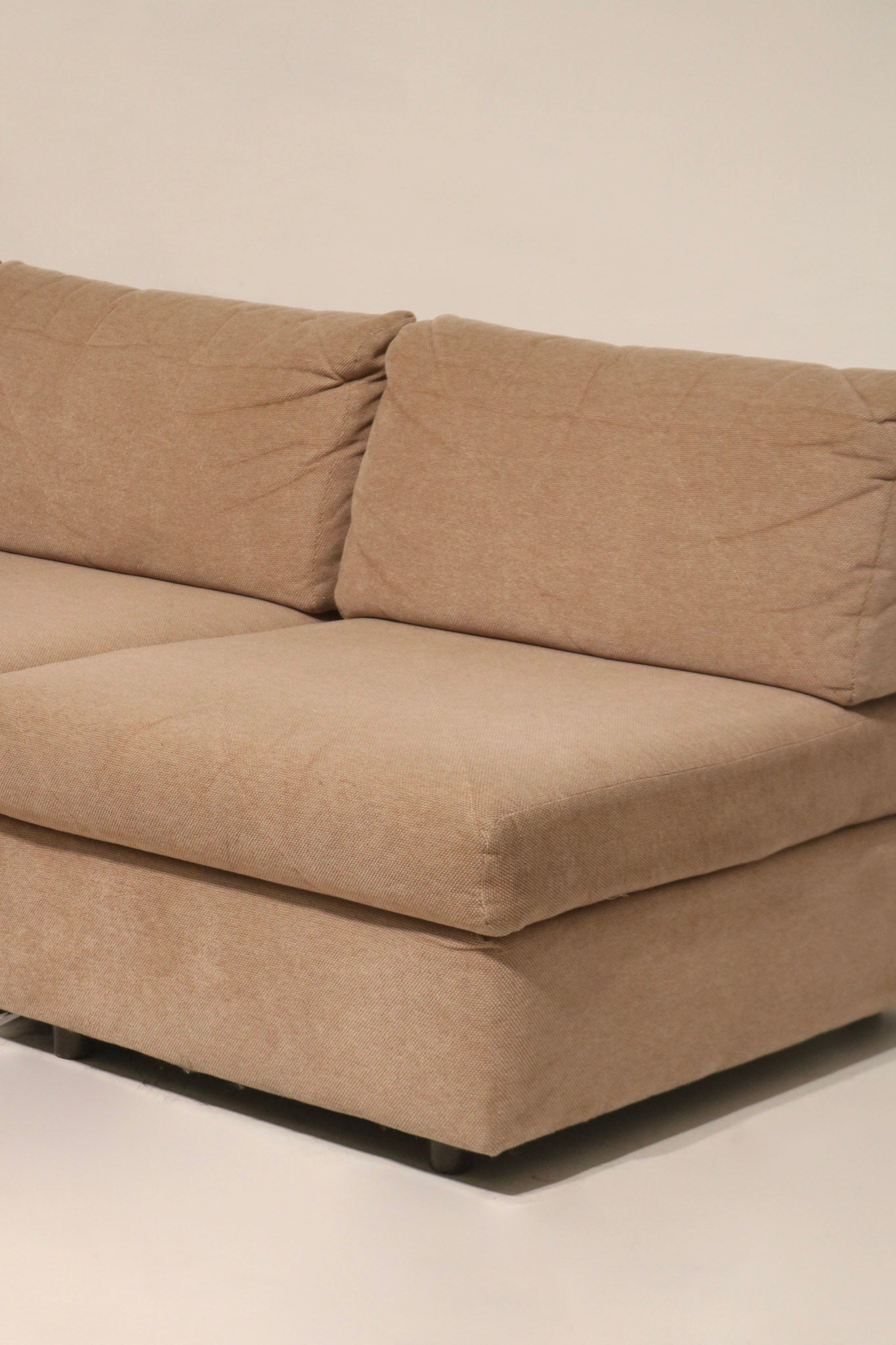 Arm profile close-up of fabric sofa couch showing rounded arm, fabric grain and edge stitching on vintage brown-pink upholstery