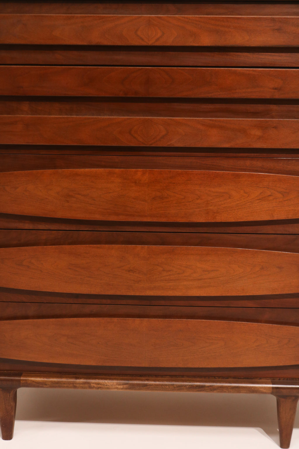 Close-up of drawer fronts with sculpted pulls highlighting walnut grain