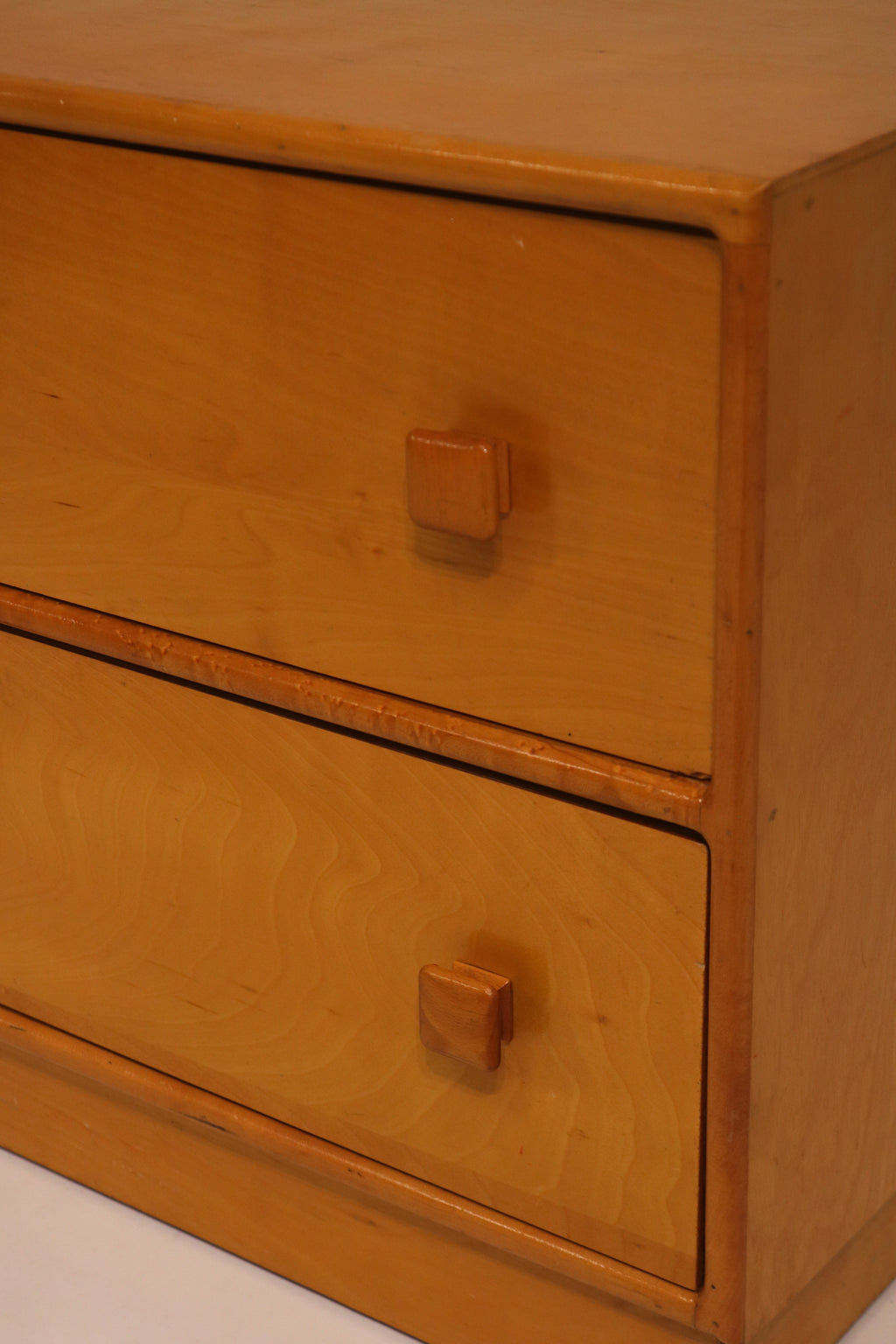Close-up of drawer fronts featuring square wooden knobs and oak grain