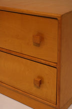 Close-up of drawer fronts featuring square wooden knobs and oak grain