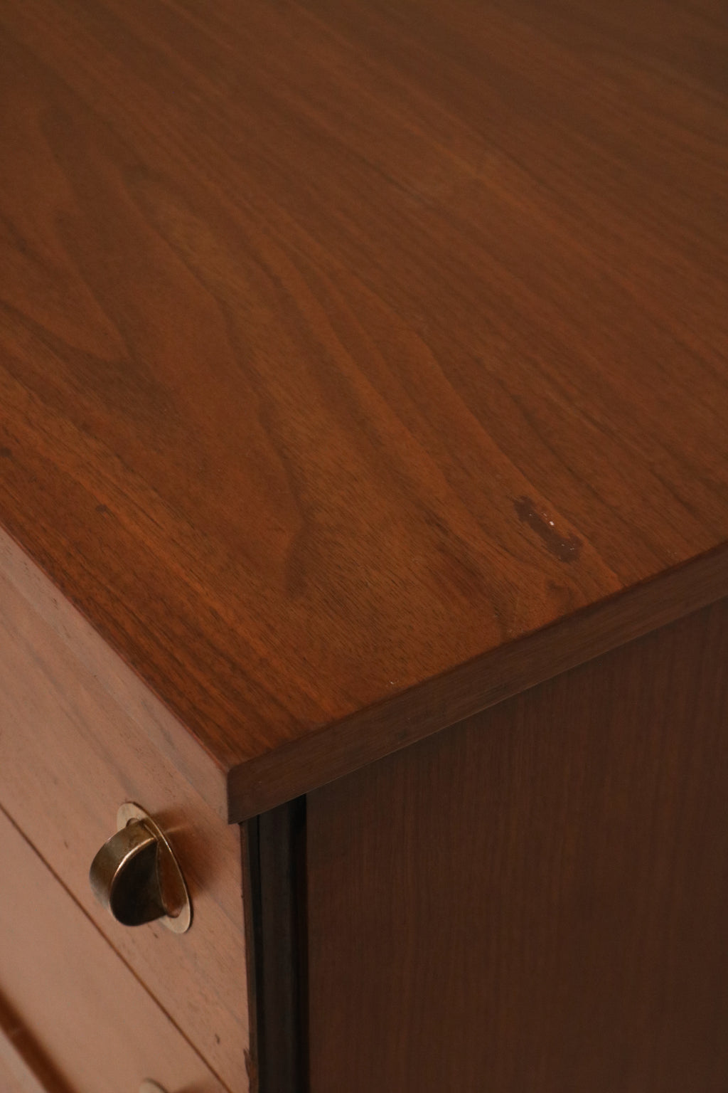Close-up of drawer fronts featuring walnut grain and original metal pulls