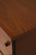 Close-up of drawer fronts featuring walnut grain and original metal pulls