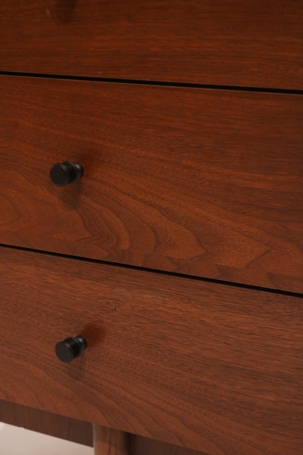 Close-up of walnut wood drawer fronts with original black knobs