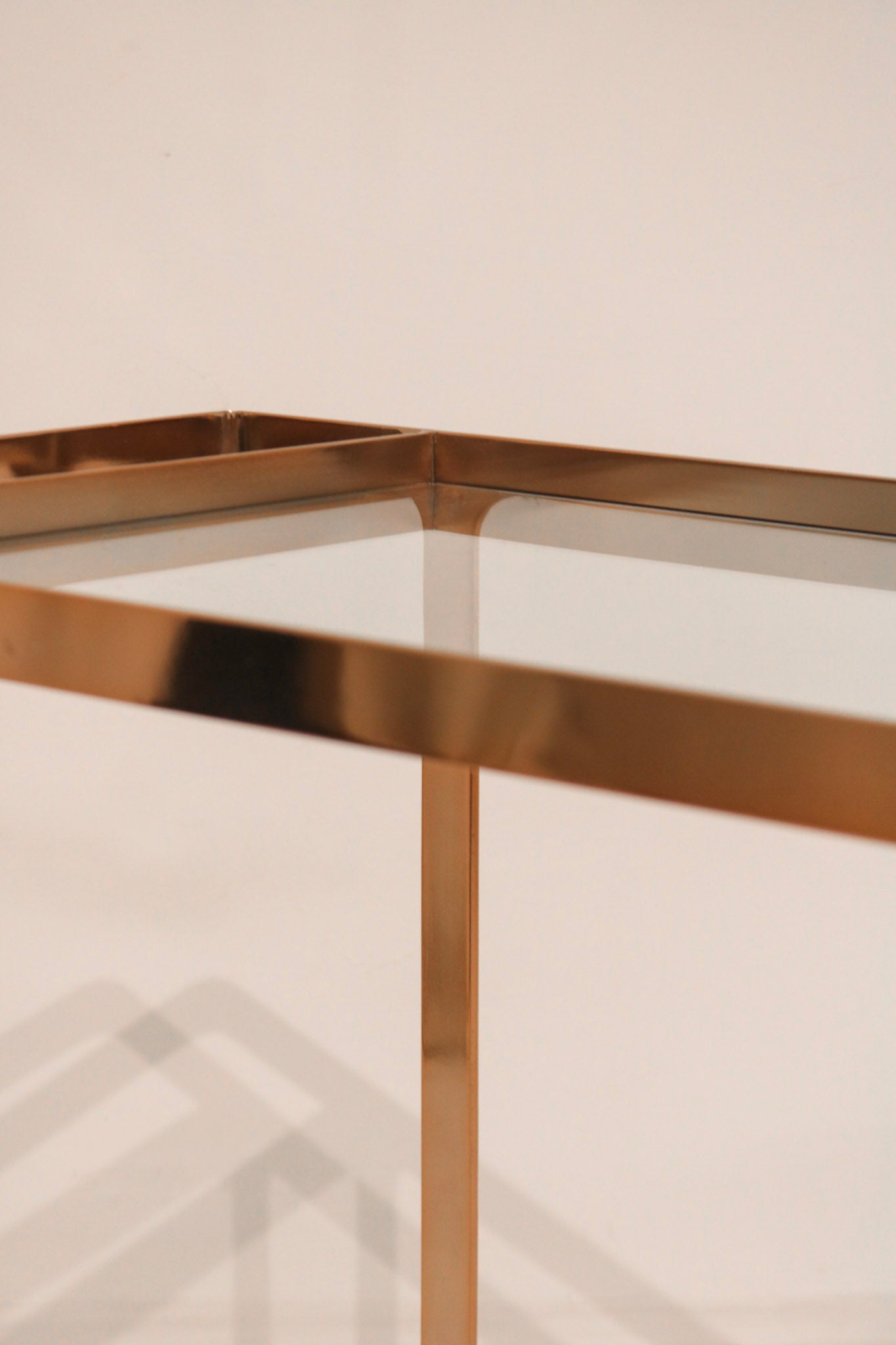 Detail of glass shelf resting on the rose gold metal frame