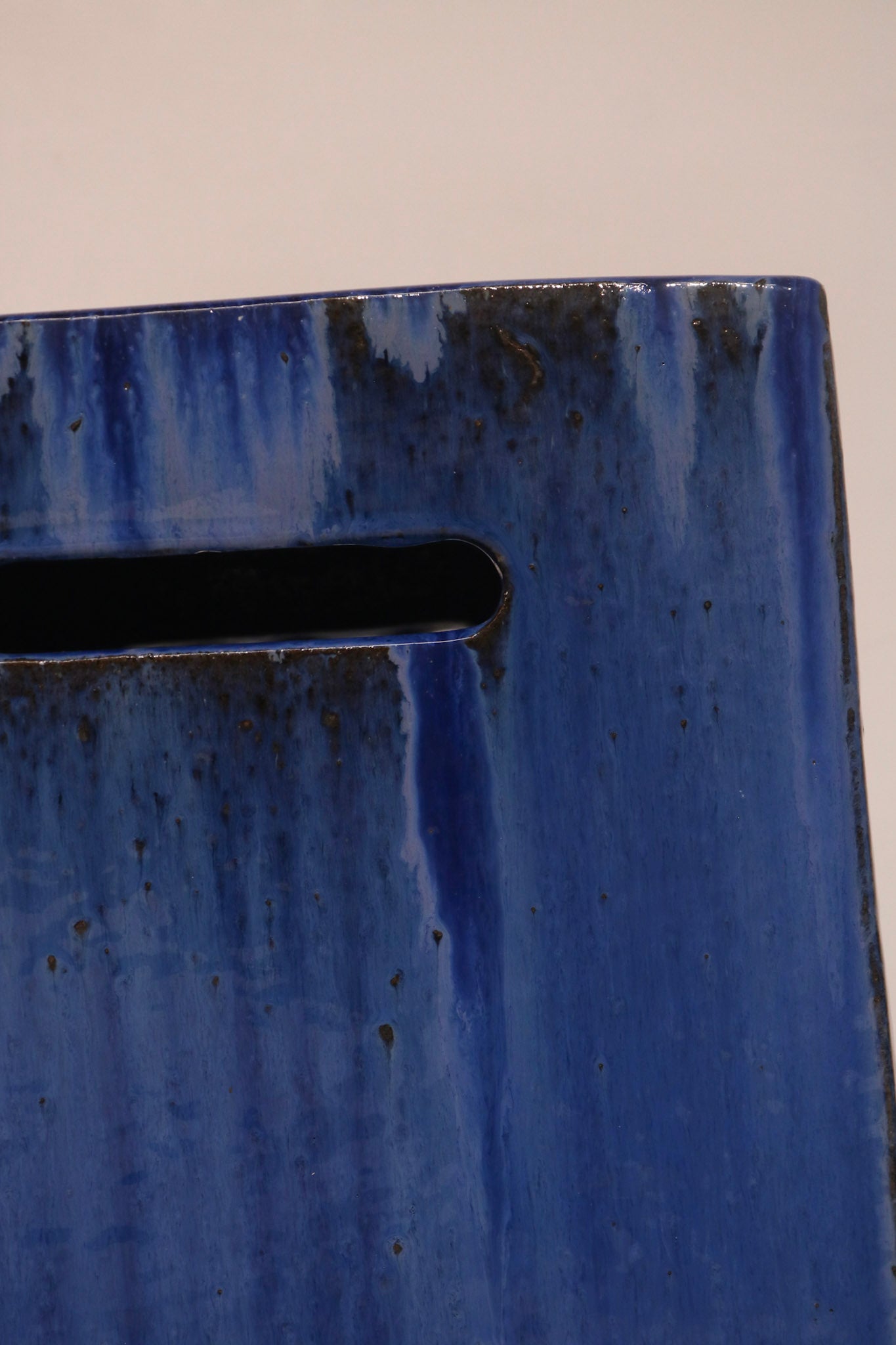 Detail of the rectangular handle cutout on the side of the ceramic stool"