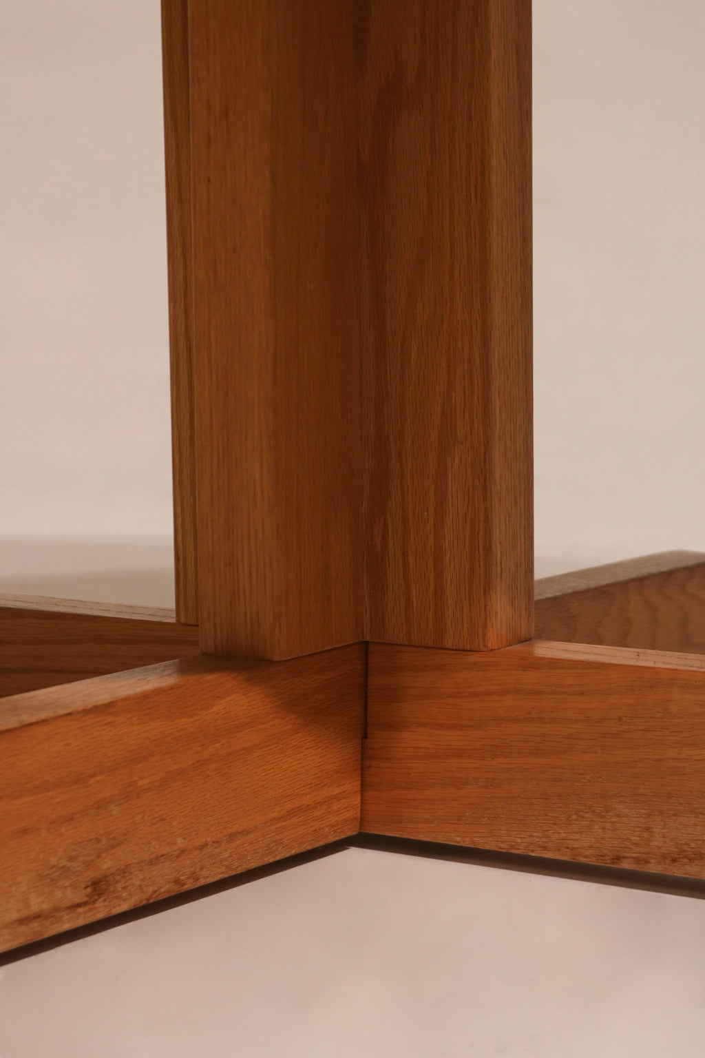 Angular profile view of oak cross base showing sturdy support and design