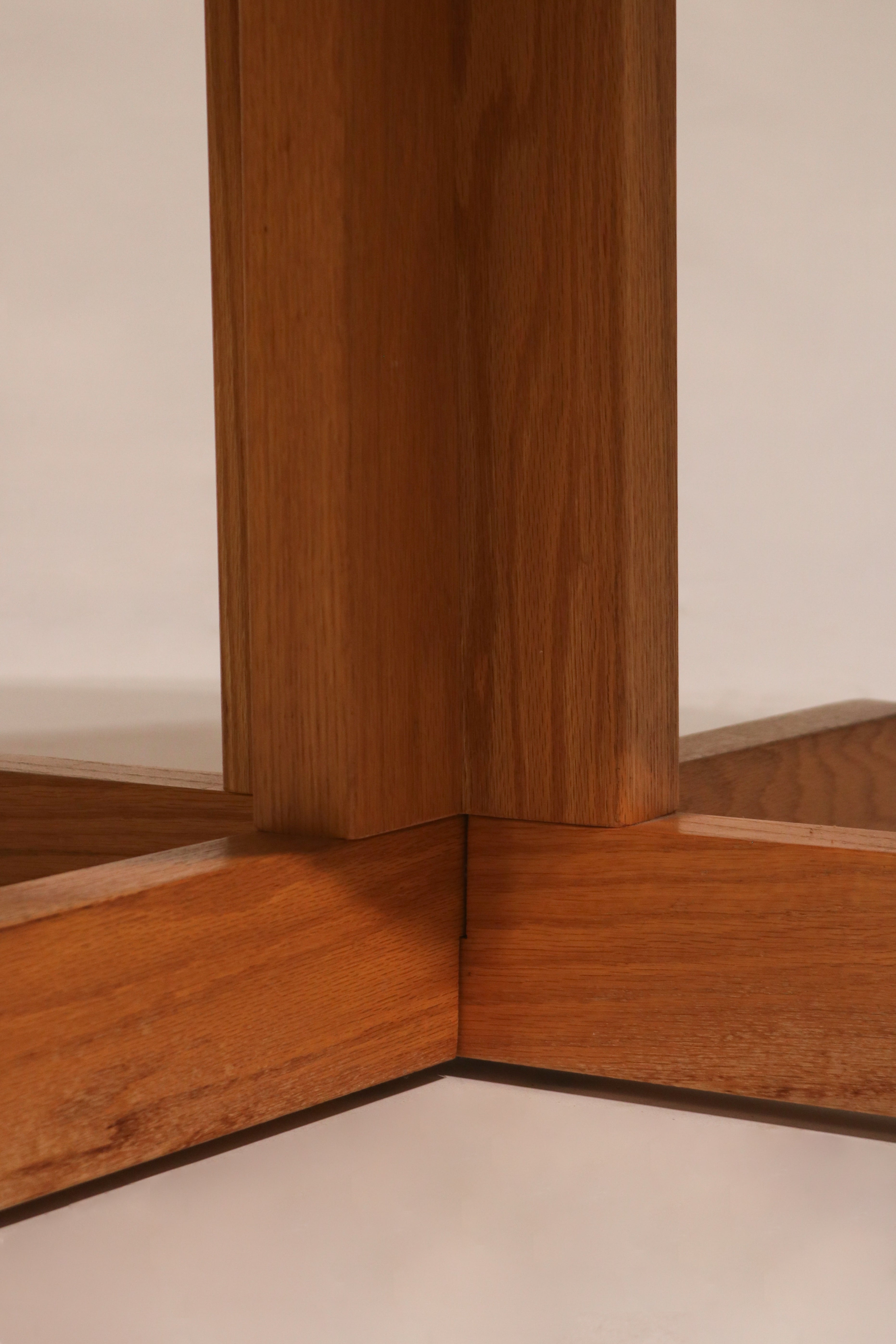 Angular profile view of oak cross base showing sturdy support and design