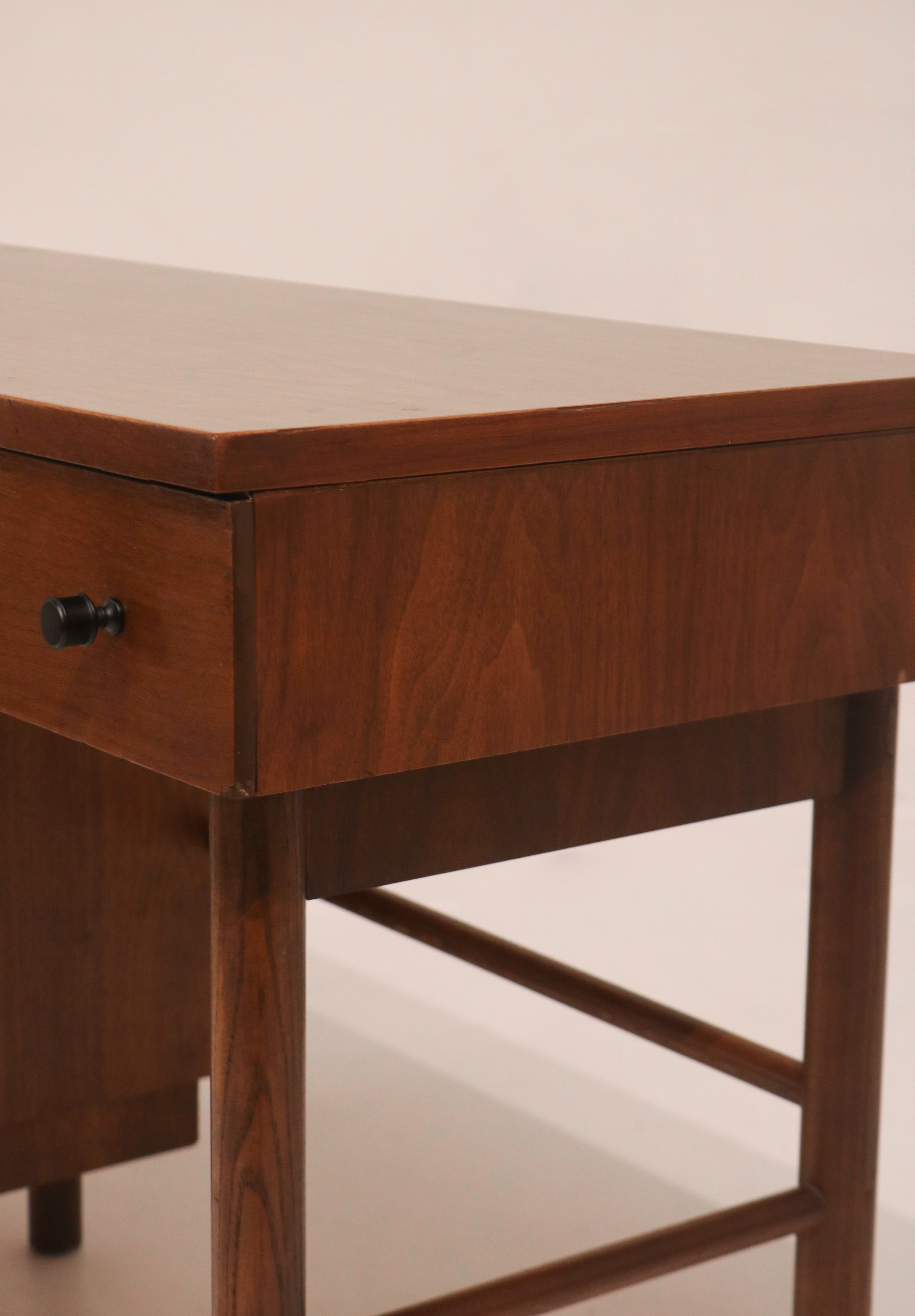 Close-up of the original black metal knob pull on walnut drawer