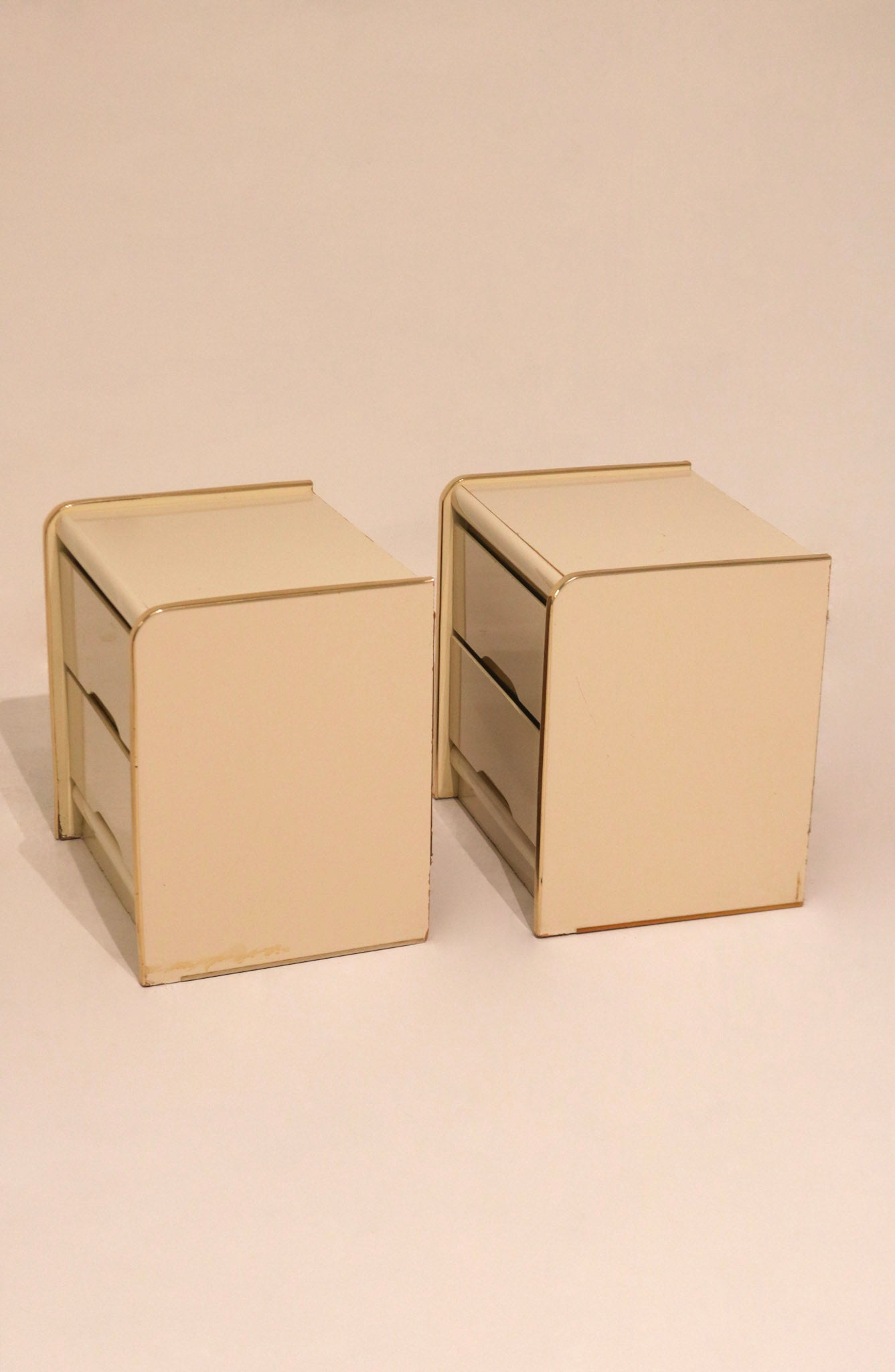 Angled view of two cream lacquer bedside tables showing matching set condition