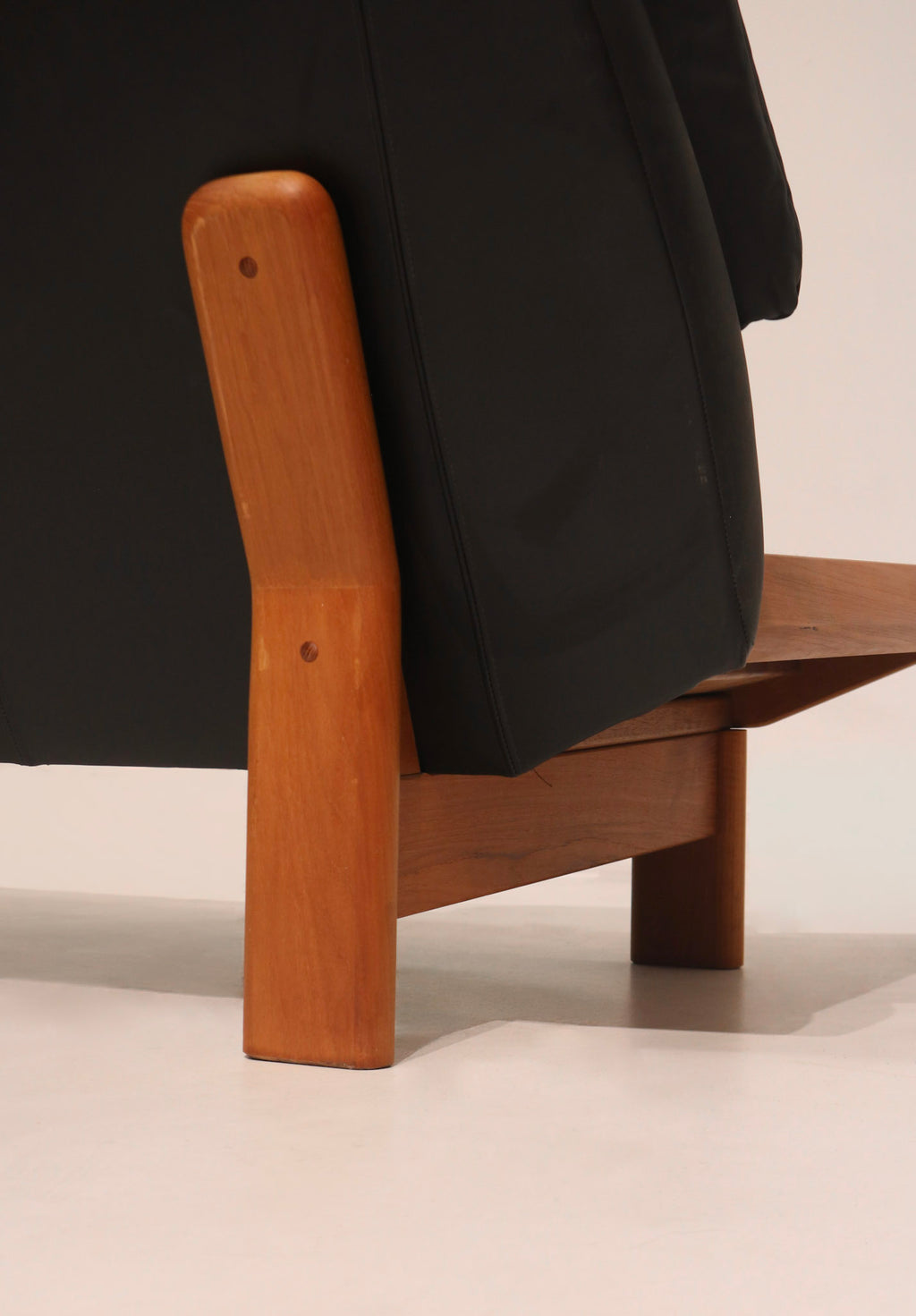 Rear profile view showing the solid teak frame structure and leather back