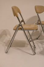 Side profile of folded chair showing chrome mechanism and slim design