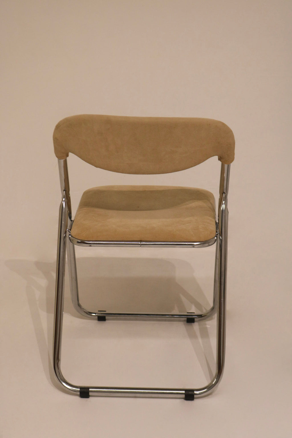 Front view of single deployed chair showing chrome frame and beige seat