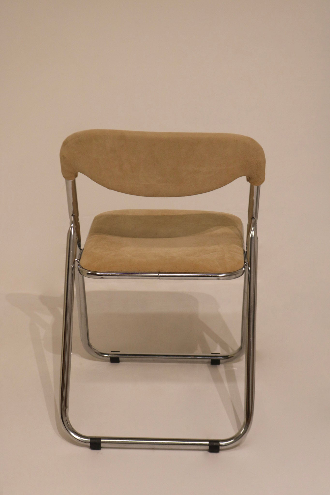 Front view of single deployed chair showing chrome frame and beige seat