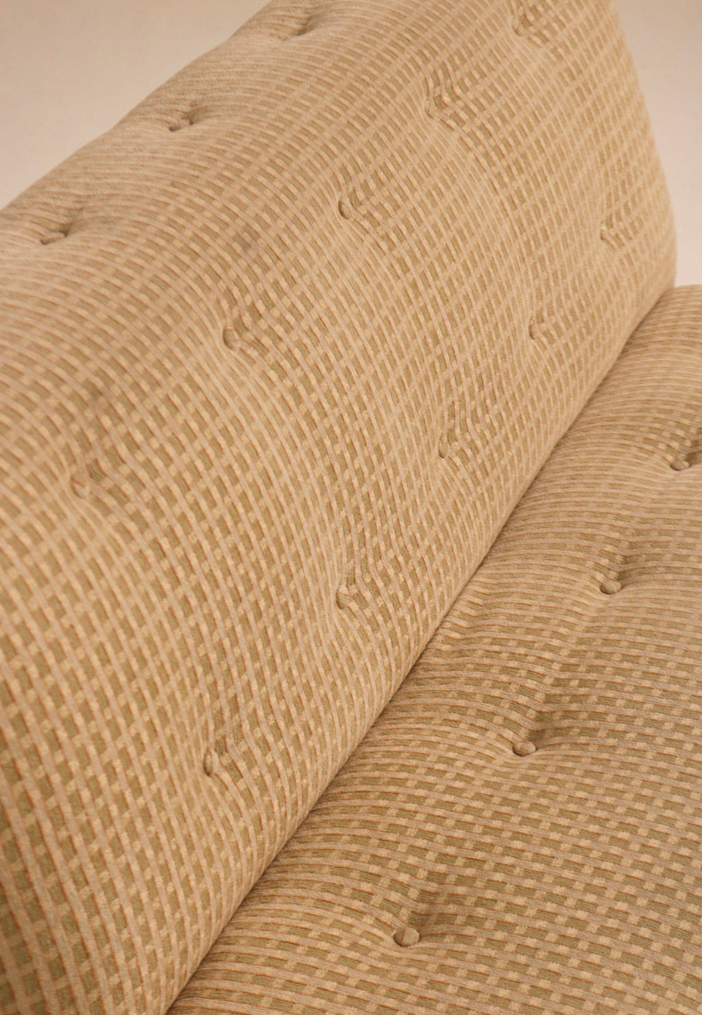Close-up of textured fabric backrest showing button tufting detail