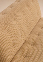Close-up of textured fabric backrest showing button tufting detail