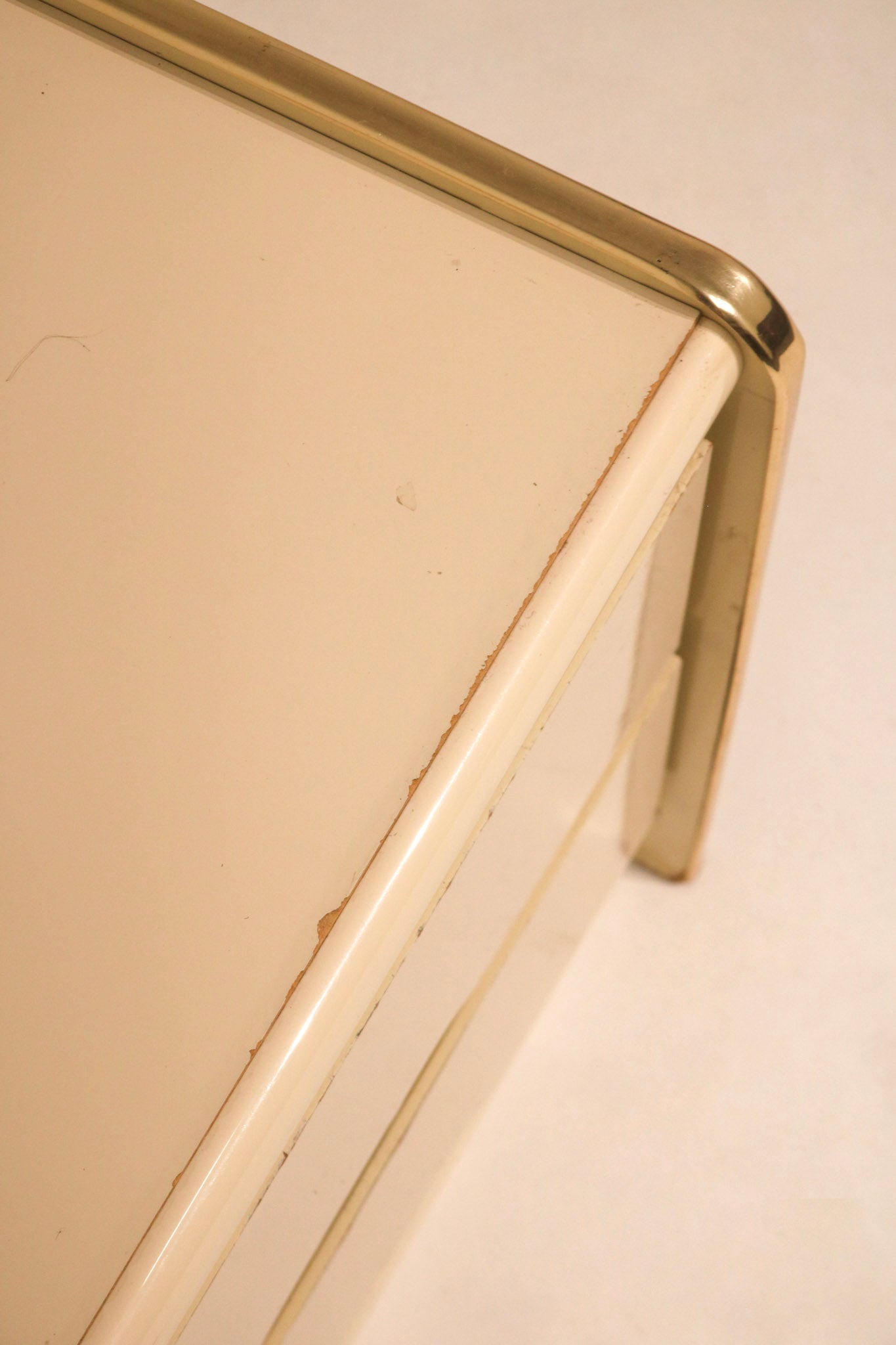 Close-up of top edge showing waterfall curve and gold brass trim detail