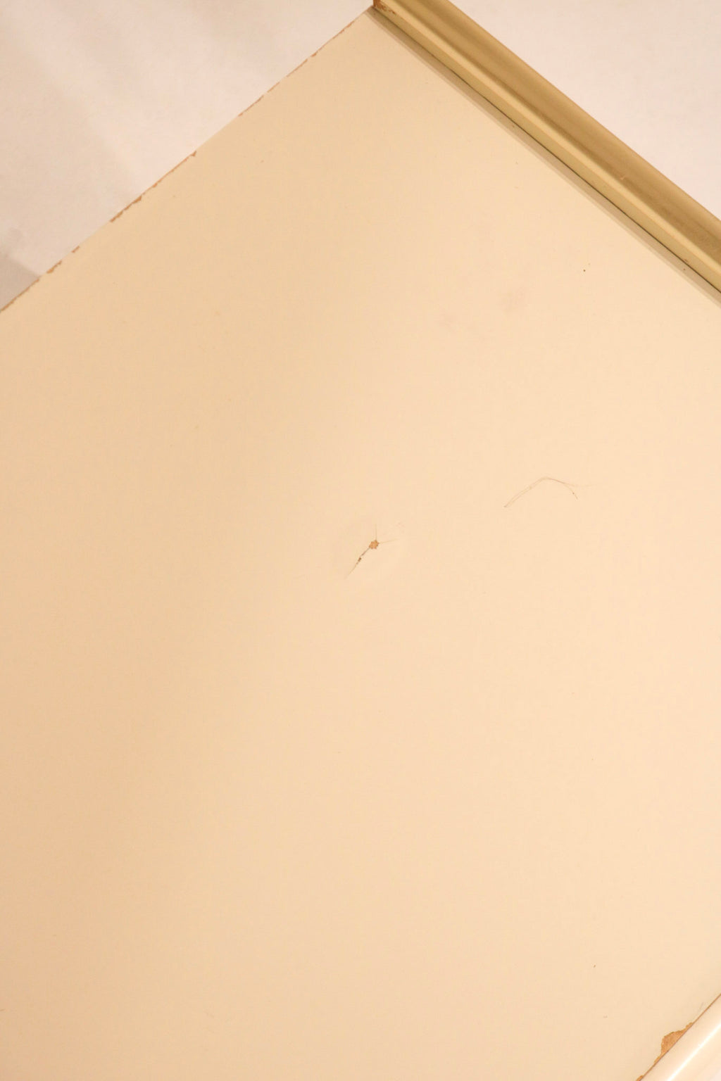 Detail of top surface showing cream lacquer finish and minor mark