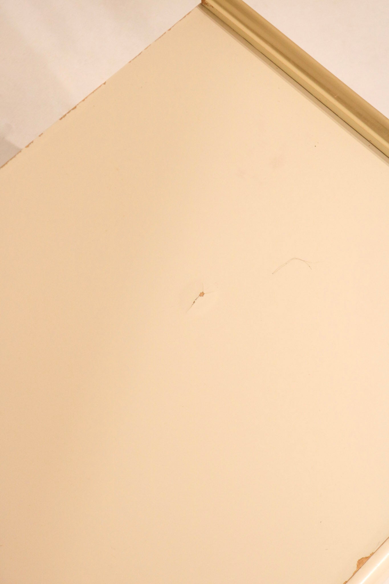 Detail of top surface showing cream lacquer finish and minor mark