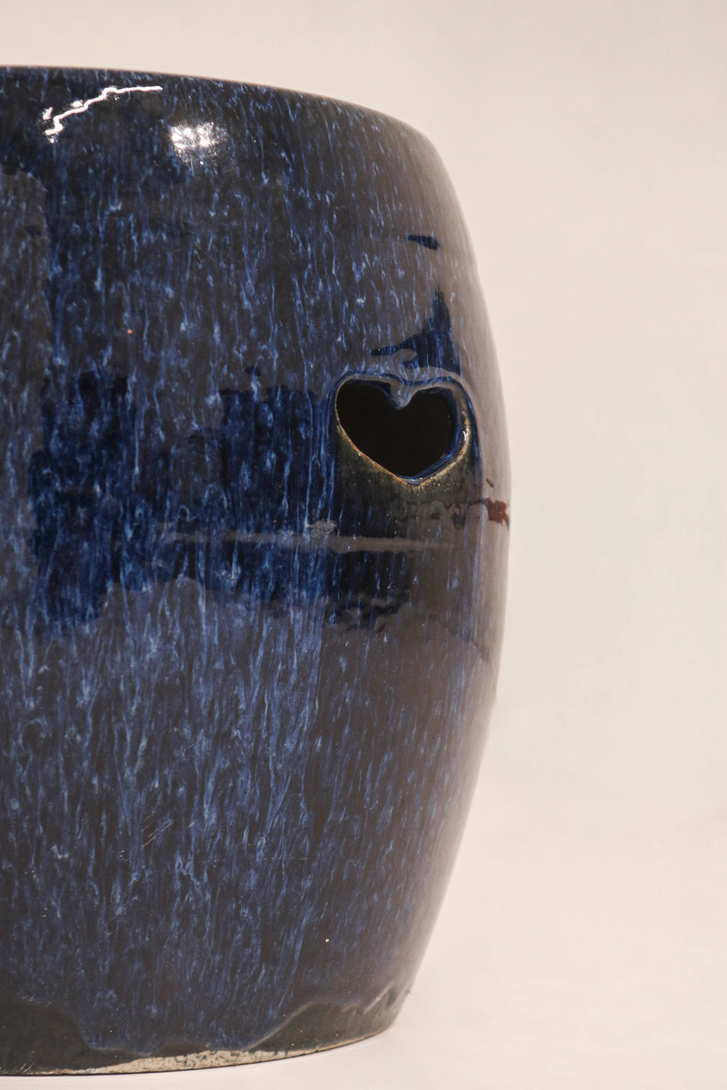 Side profile view blue ceramic garden stool showing barrel shape and pierced details