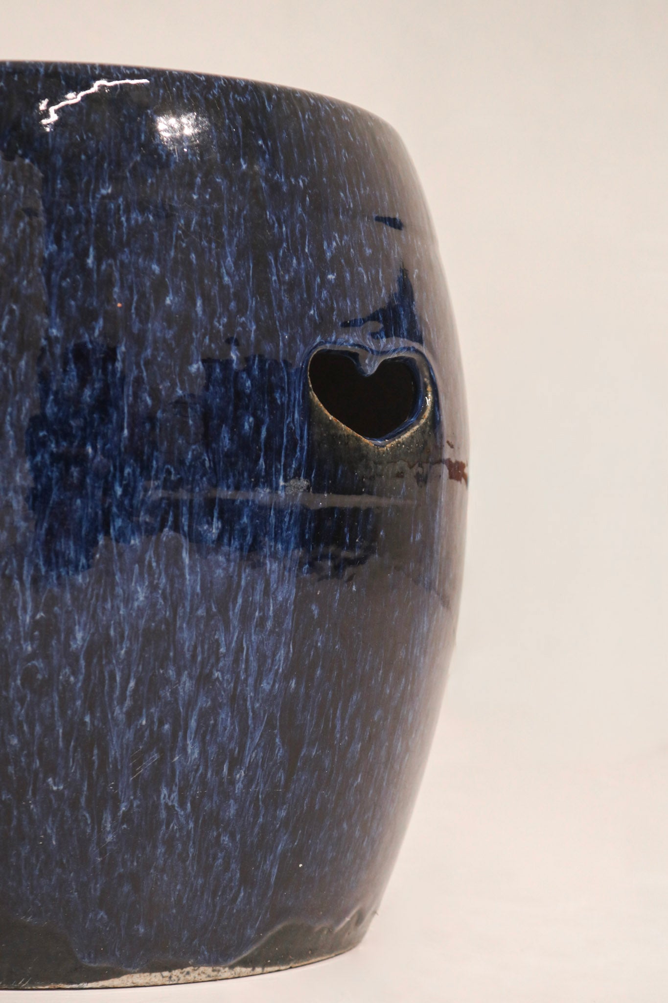 Side profile view blue ceramic garden stool showing barrel shape and pierced details